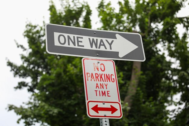 Un panneau de rue à sens unique qui dit qu'il est interdit de se garer à tout moment.