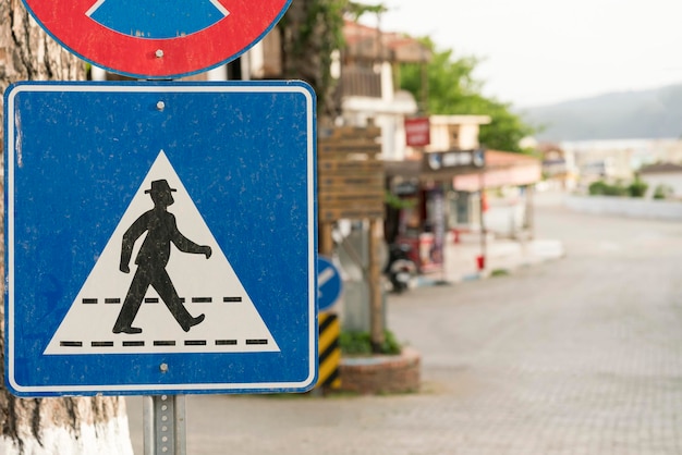 Panneau de signalisation carré bleu avec une figure masculine noire portant un chapeau marchant sur le passage pour piétons