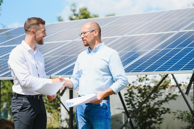 Le panneau solaire de la ferme solaire avec deux ingénieurs à pied pour vérifier le fonctionnement du système Énergie alternative pour conserver l'énergie mondiale Idée de module photovoltaïque pour la production d'énergie propre