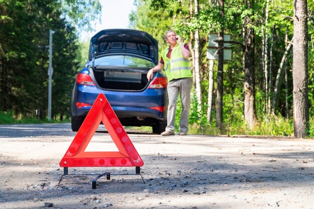 Panneau triangulaire d'avertissement portatif sur le côté d'une route rurale près d'une voiture