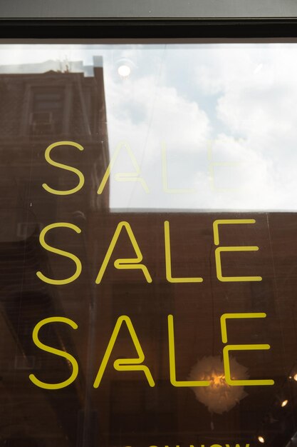 Photo un panneau de vente au néon jaune sur une vitrine