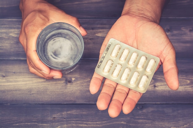 panneaux de pilules avec des capsules et un verre d&#39;eau dans la main d&#39;un homme