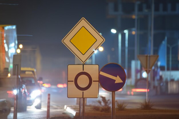 Panneaux routiers ronds-points avec des voitures floues sur la circulation urbaine la nuit Concept de transport urbain