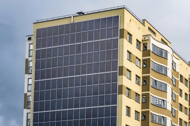 Panneaux solaires sur le mur d'un bâtiment à plusieurs étages sur fond de nuages d'orage Énergie solaire renouvelable une maison économe en énergie qui utilise l'énergie de l'air et des eaux usées du soleil de la terre