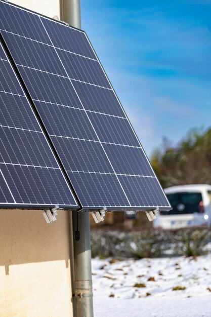 Panneaux solaires avec de la neige sur le sol sur un mur bien exposé d'une maison individuelle faisant des économies à la suite de la crise énergétique geste écocitizen énergie verte