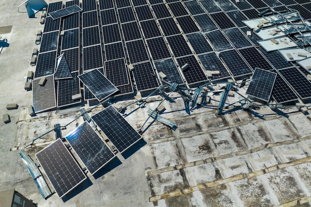 Panneaux solaires photovoltaïques en panne détruits par les vents de l'ouragan Ian montés sur le toit d'un bâtiment industriel pour produire de l'électricité écologique verte Conséquences d'une catastrophe naturelle