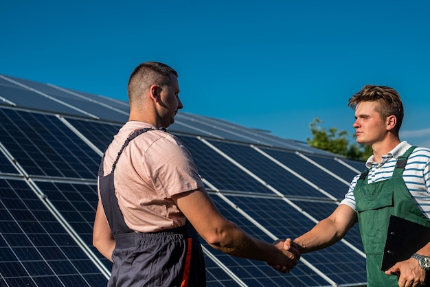 Panneaux solaires avec poignées de main en gros plan. Accord sur l'installation d'une nouvelle station