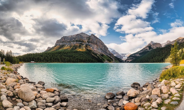 Panorama du lac Louise avec des montagnes rocheuses et un ciel bleu ensoleillé au parc national Banff, Canada