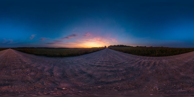 Panorama hdri sphérique complet et harmonieux à 360 degrés sur la route goudronnée parmi les champs au coucher du soleil d'été avec des nuages impressionnants en projection équirectangulaire prêt pour la réalité virtuelle VR AR