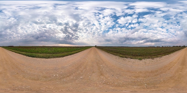 Panorama hdri sphérique complet et harmonieux à 360 degrés sur la route de gravier parmi les champs en automne avec de beaux nuages en projection équirectangulaire prêt pour le contenu de réalité virtuelle VR AR