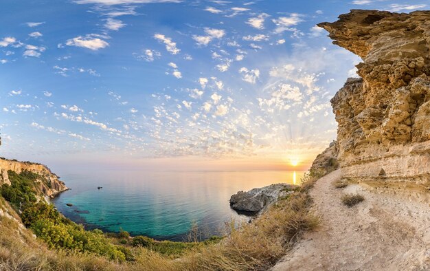 Panorama à l'heure du coucher du soleil avec de beaux nuages dans la baie rocheuse avec une mer azur cristalline sur un