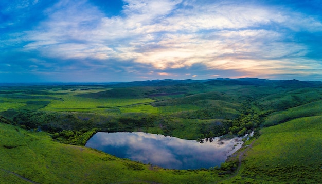 Le panorama sur le lac à l'eau claire est situé entre des collines verdoyantes d'herbe dans les montagnes des Balkans sous un ciel nuageux