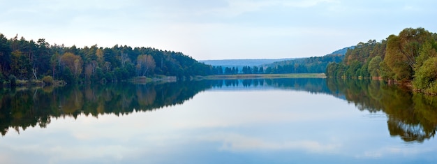 Panorama de lac de soirée brumeuse d'automne avec le bosquet sur le rivage. Deux clichés piquent l'image.