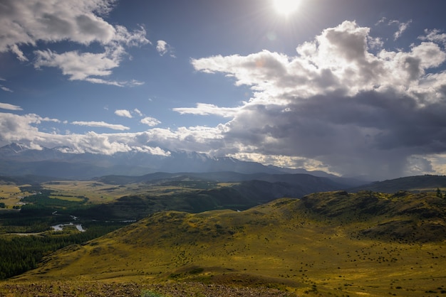 Panorama majestueux de la plaine de montagne sur fond de crête enneigée avant l'orage.