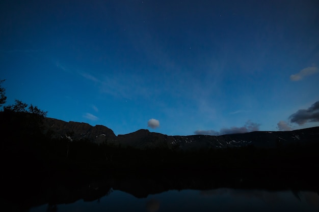 Panorama nocturne avec les montagnes du Khibiny, ciel reflété dans le lac Petit Vudyavr. Péninsule de Kola, Russie.