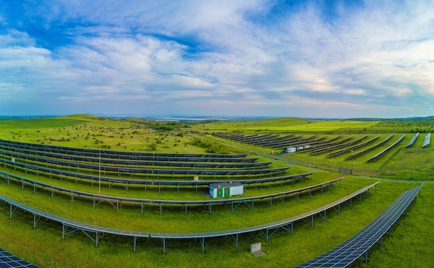 Panorama sur des panneaux solaires pour générer de l'énergie à partir des rayons du soleil sont installés dans les prés sous un ciel bleu avec soleil