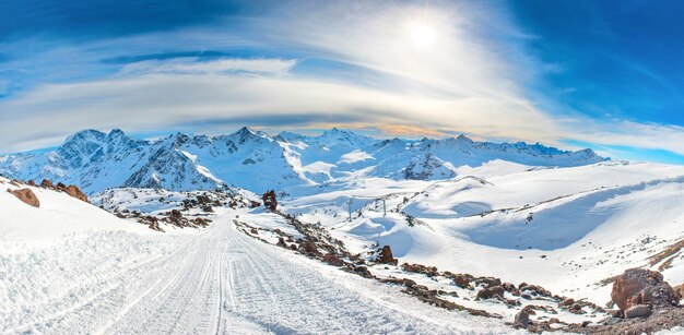 Panorama des pics d'hiver de neige dans la chaîne de montagnes. Paysage avec ciel coucher de soleil et nuages