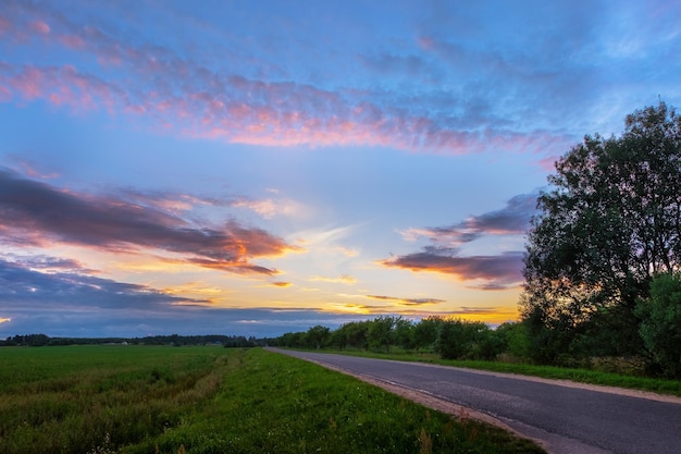 Panorama de route asphaltée dans la campagne au coucher du soleil en été. Route dans un magnifique paysage naturel.