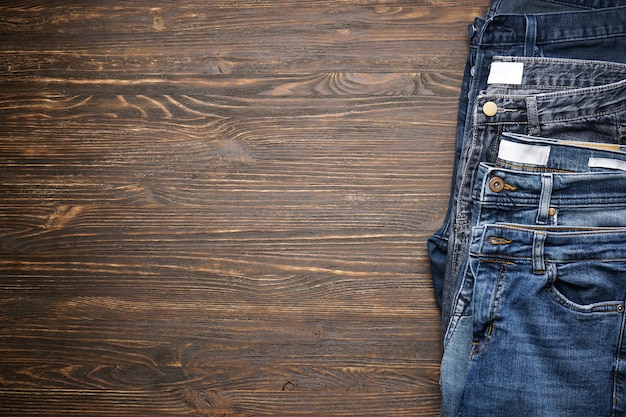 Pantalon en denim plié sur table en bois, espace pour le texte. Mise à plat.