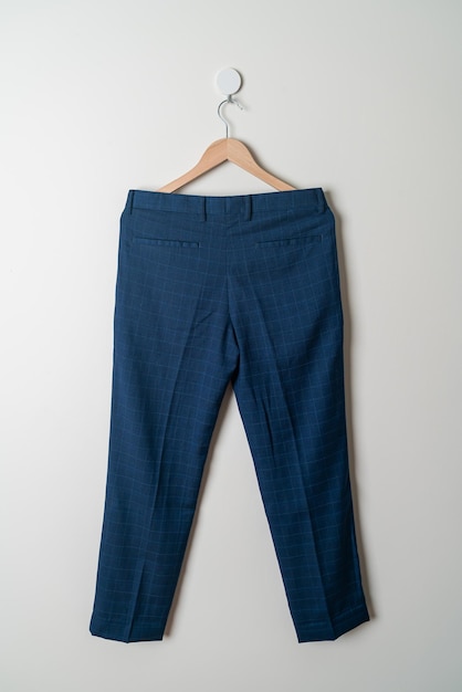 Photo pantalon ou pantalon long suspendu avec un cintre en bois au mur