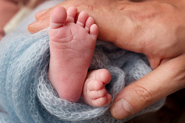 Papa aimant tient les jambes de bébé. Enfance heureuse. Soins parentaux. Concept d'une famille heureuse.