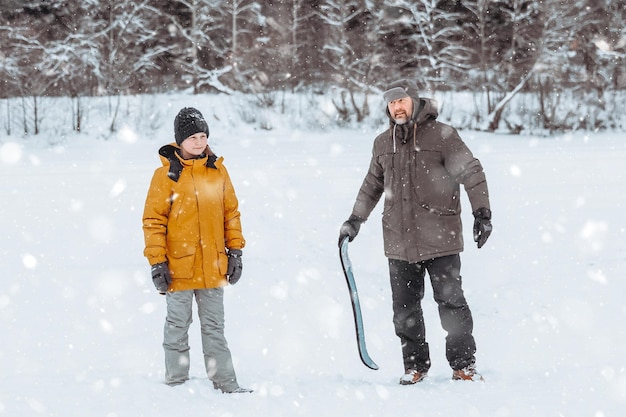 Papa apprend à sa fille à faire du patin à neige dans une promenade familiale au parc d'hiver au grand air