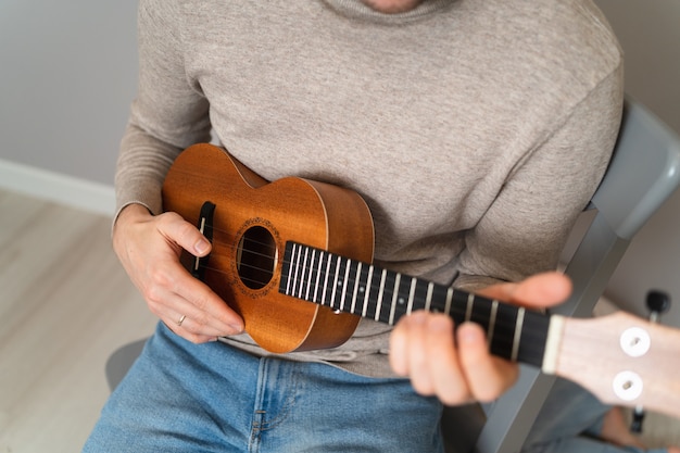 Papa apprend à sa fille à jouer du ukulélé. Enseignement à domicile pour jouer de la guitare. Gros plan des cordes et des mains de ukulélé.