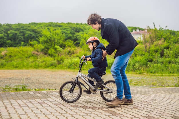 Papa apprend à son fils à faire du vélo dans le parc.