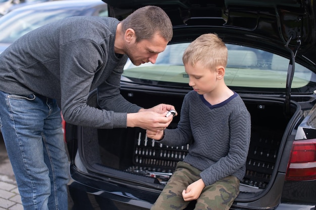 Papa apprend à son mignon fils à utiliser un outil de réparation de voiture