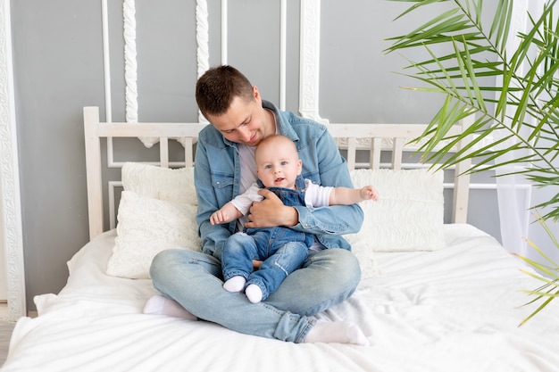 Papa avec un bébé dans ses bras à la maison sur le lit, paternité heureuse