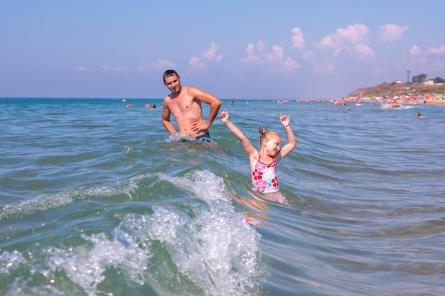 Papa et enfant s'amusent en mer. Père et fille sur la plage par une journée ensoleillée.
