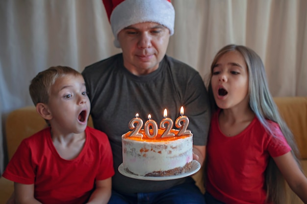 Papa avec des enfants avant le gâteau de noël avec des numéros de famille célébration du nouvel an fond festif