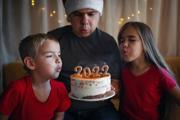 Papa avec des enfants avant le gâteau de noël avec des numéros de famille célébration du nouvel an fond festif