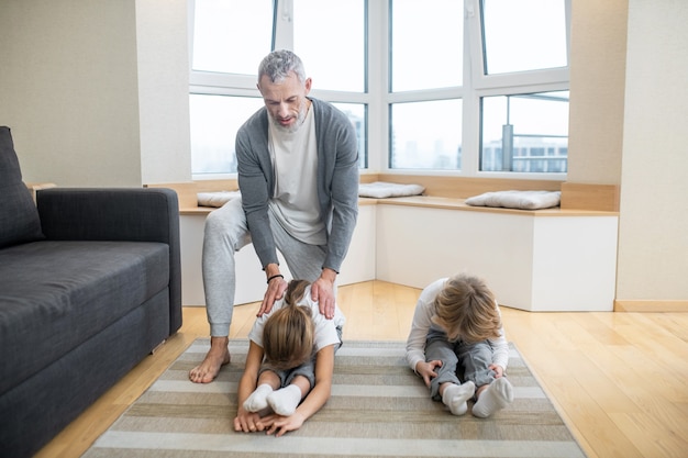 Papa enseigne aux enfants des exercices de yoga à la maison