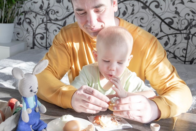 Un papa fête Pâques avec son jeune fils Ils battent des oeufs mangent des oeufs et prennent le petit déjeuner Papa enseigne à l'enfant