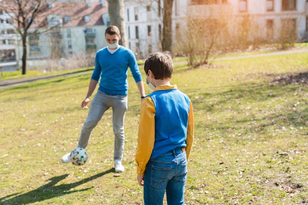 Papa et fils jouent au soccer dans le parc pendant la crise des coronavirus