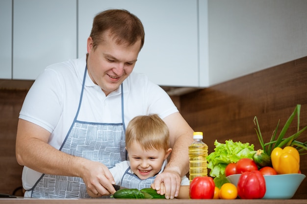 Papa et fils préparent une salade dans la cuisine