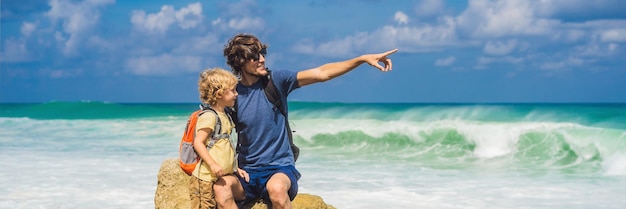 Papa et fils voyageurs sur l'incroyable plage de melasti aux eaux turquoises de l'île de bali indonésie voyageant