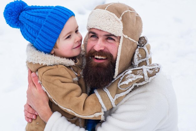 Photo papa et garçon souriant et étreignant le fils de la famille heureuse embrasse son père pendant les vacances d'hiver