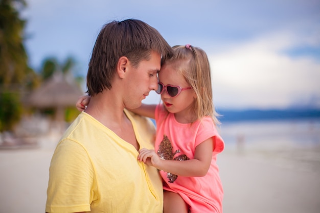 Papa heureux et sa petite fille à la plage de sable blanc