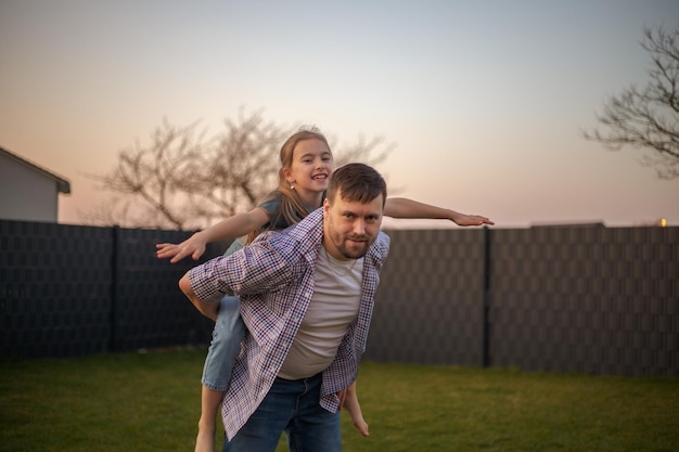 Papa joue avec sa fille dans le jardin de la maison