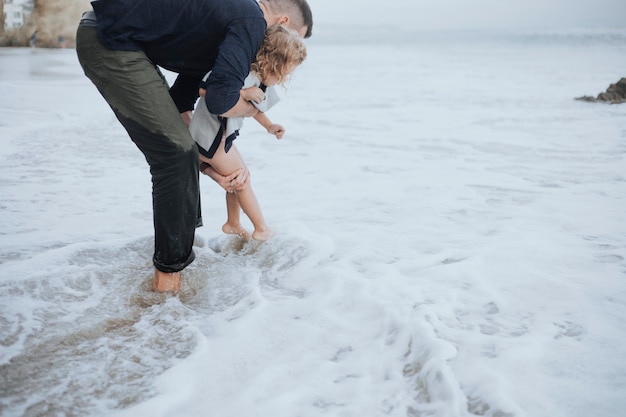 Papa joue avec sa fille et les vagues