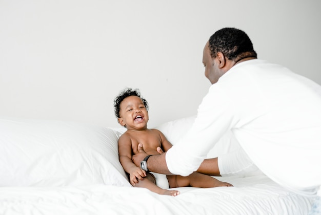 Papa joue avec son bébé sur le lit