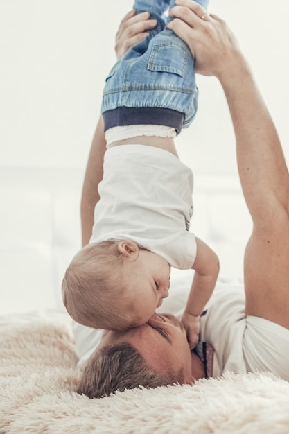 Papa joue avec son fils bien-aimé. Papa tient le gamin par les pieds