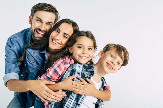 Papa et maman les étreignant beaux enfants et regardant la caméra