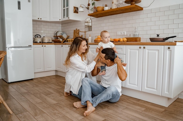 papa et maman jouant avec le bébé sur le sol de la cuisine