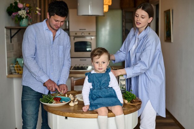 Papa maman et leur fille cuisinent des pizzas ensemble dans la cuisine Le concept d'une famille heureuse