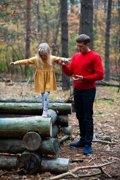 Papa et maman avec leur fille se promènent à l'automne dans la forêt Famille dans la nature