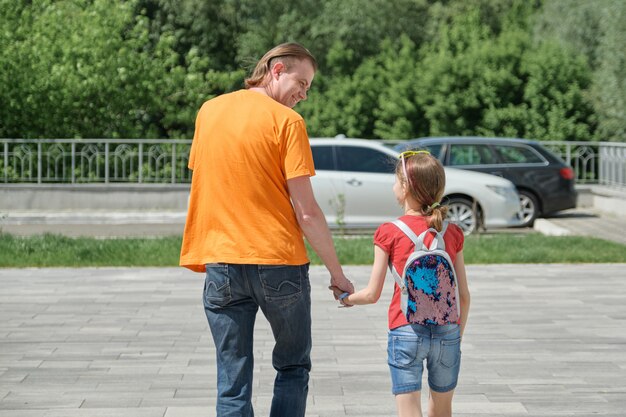 Papa marche avec sa fille se tenant la main