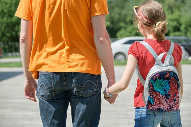 Papa marche avec sa fille se tenant la main